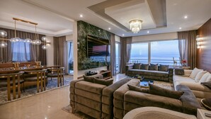 Un salon moderne doté d’un grand canapé, d’un coin repas et offrant une vue sur la mer.