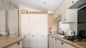 A modern kitchen with white cabinets, a wooden countertop, and a gas stove. - The Goodwood Lodge (Chichester)
