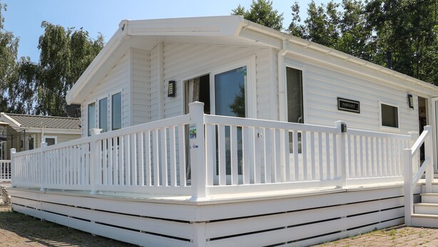 A white mobile home with a covered porch and a small deck. - The Goodwood Lodge (Chichester)