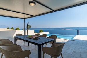 Una terraza con mesa y sillas, una piscina y vistas al mar.