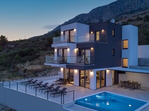 Una casa moderna de varios pisos con piscina, balcones y comedor.