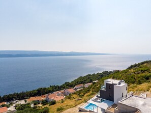 Una proprietà costiera con un edificio moderno, una piscina e vista sul mare.