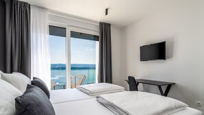 A hotel room with two beds, a TV, a desk, and a balcony with a view of the sea. - Seaview Villa Marila with a private heated pool with hydromassage, 3 en-suite bedrooms (6+2 people), 1km from the beach (Lokva Rogoznica ( Omis))