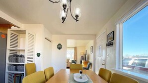 A dining room with a wooden table, yellow chairs, a chandelier, and a view through a window. - Kanab Utah home with HUGE fenced in backyard-Pets Welcome! Near National Parks! (Kanab)