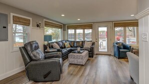 A spacious living room with a sectional sofa, a recliner, and a patterned ottoman. - Relax in Raymond's lakefront 2-bedroom vacation home, just steps to Sebago Lake (Raymond)