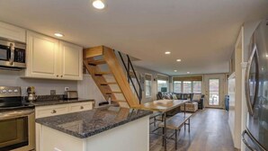 A modern kitchen with granite countertops, stainless steel appliances, and a wooden staircase. - Relax in Raymond's lakefront 2-bedroom vacation home, just steps to Sebago Lake (Raymond)