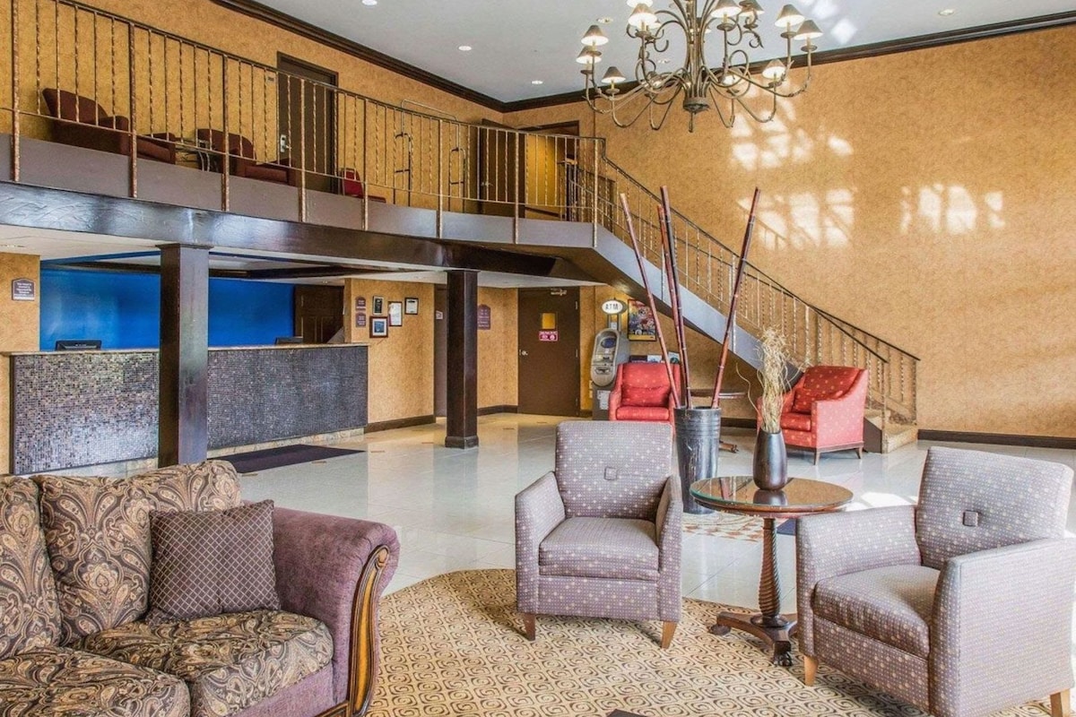 A hotel lobby with a staircase, seating area, and a reception desk.
