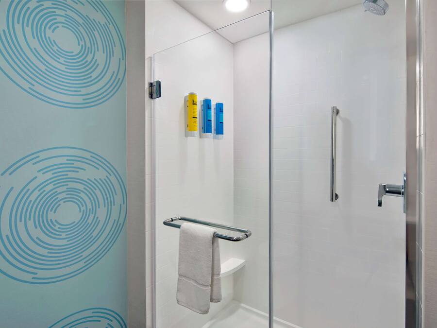 A modern bathroom with a glass shower enclosure, a white toilet, and a towel rack.