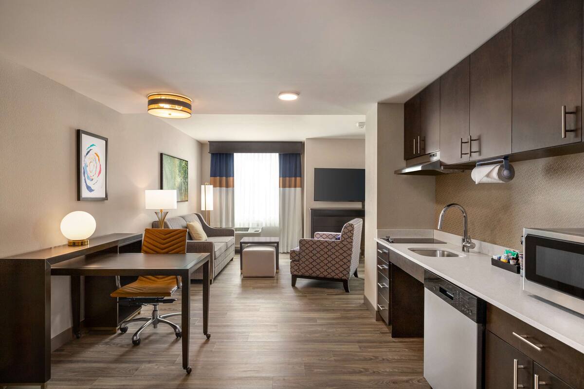 Une chambre d’hôtel moderne dotée d’une kitchenette, d’un coin repas et d’un espace de vie.
