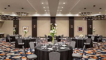 A conference room with multiple tables, chairs, and floral centerpieces.