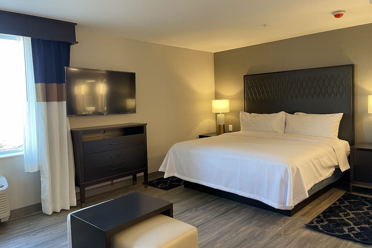 Une chambre d’hôtel avec un lit, un bureau, une chaise, une télévision et une lampe.