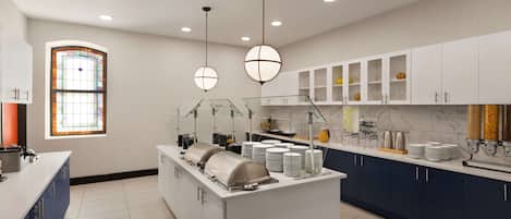 A modern kitchen with a central island, white cabinets, and a large window with stained glass.