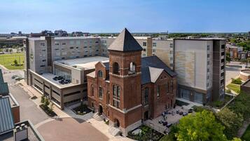 A multi-story building with a prominent brick tower and a flat-roofed structure.