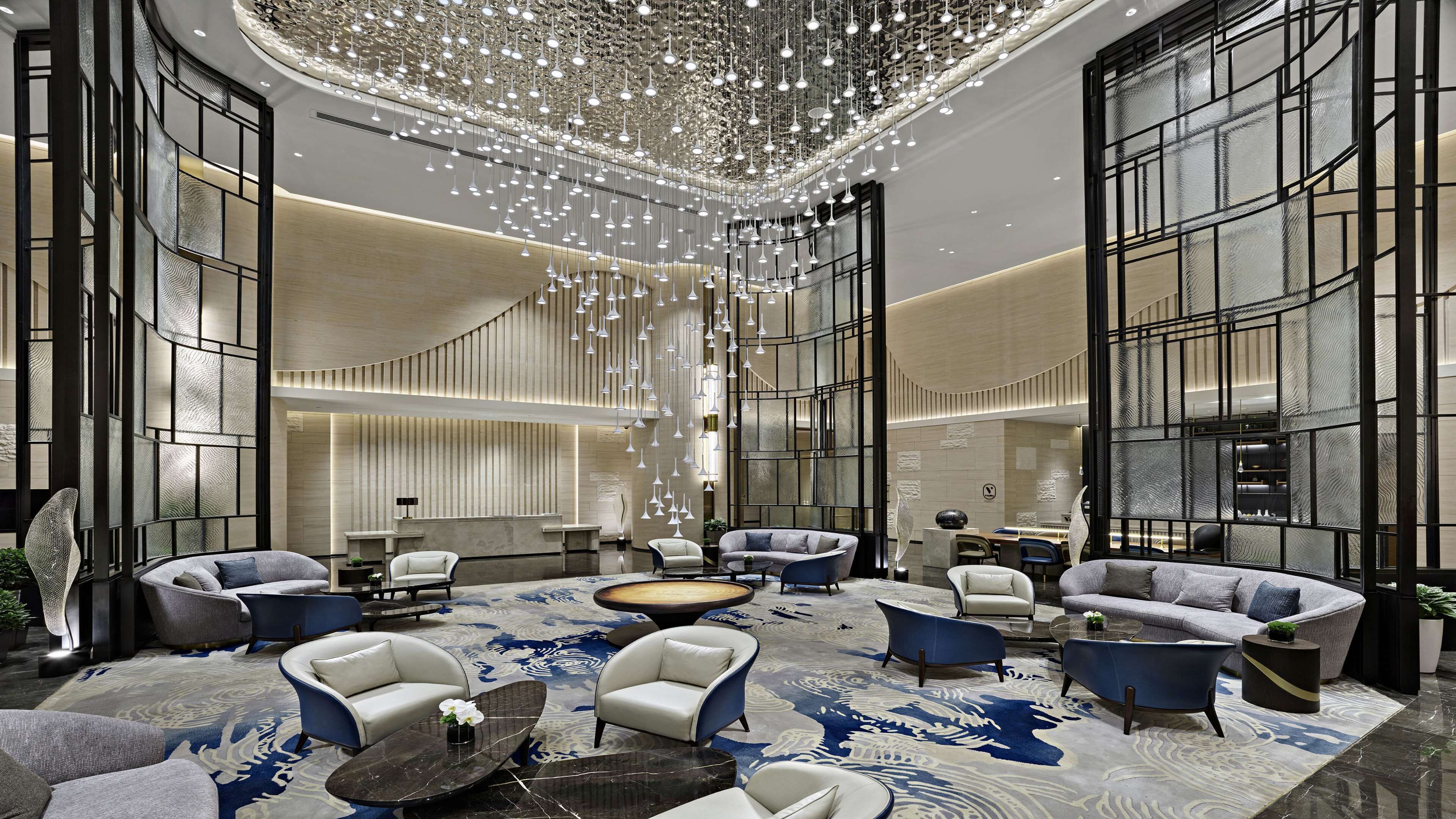 A spacious lobby with modern seating, a large chandelier, and a patterned carpet.