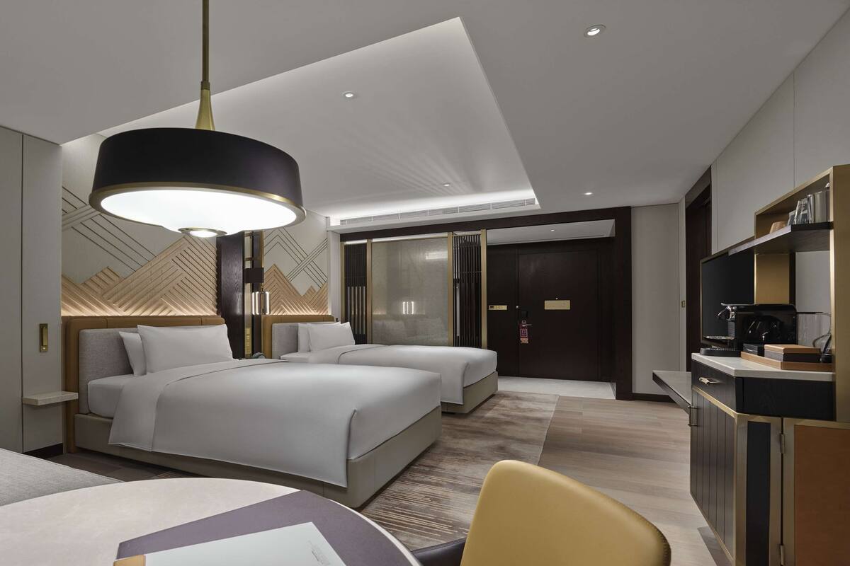 Une chambre d’hôtel moderne équipée d’un grand lit, d’un lit plus petit, d’un bureau et d’un coin salon.