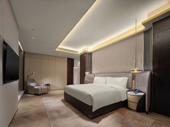 Ein modernes Hotelzimmer mit einem großen Bett, Nachttischen, einem Fernseher und einer Sitzecke.