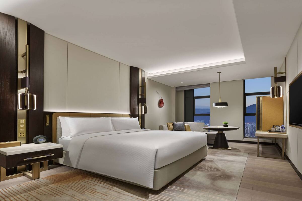 Une chambre d’hôtel moderne avec un grand lit, un bureau et une télévision.
