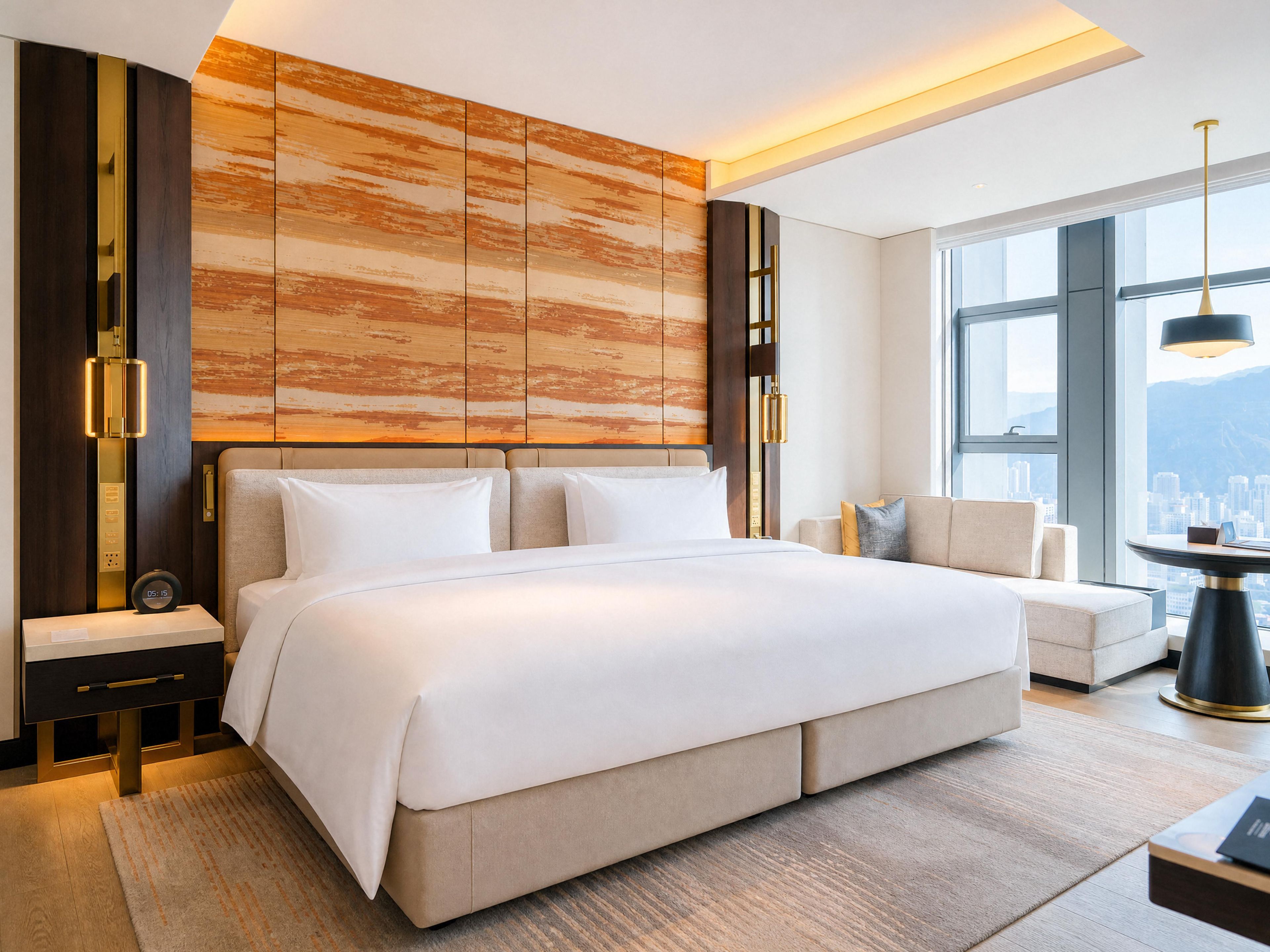 Habitación de hotel moderna con una cama grande, un sofá, una mesa de comedor y vista a la ciudad.