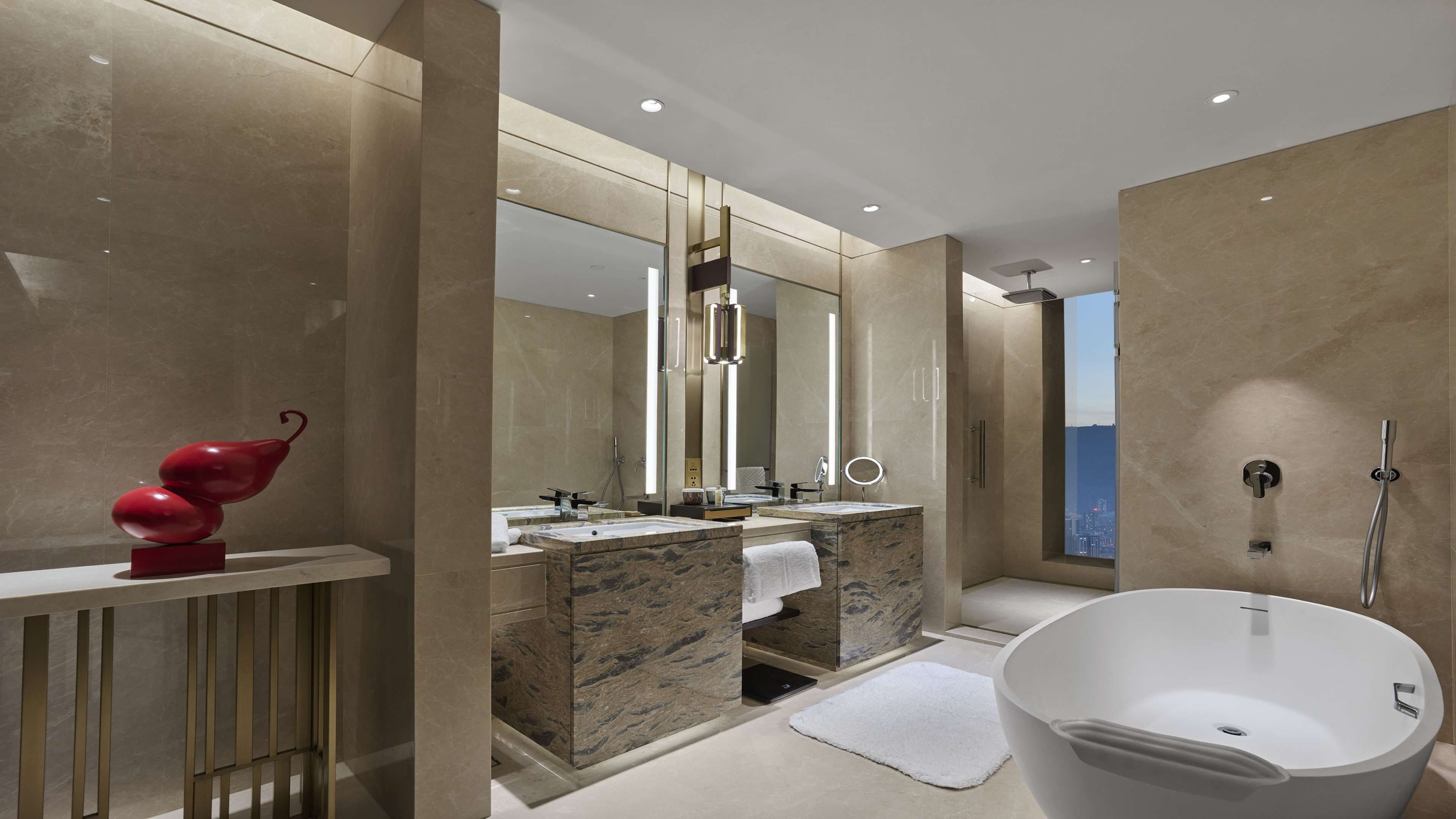 A modern bathroom with a freestanding bathtub, a vanity with a marble countertop, and a large mirror.