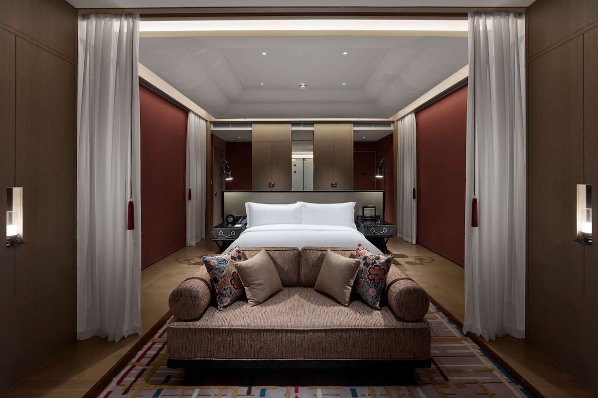 Um quarto de hotel espaçoso com uma cama grande, um sofá e um espelho.