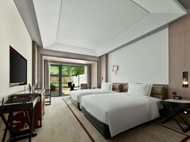 Habitación de hotel moderna con dos camas, un escritorio, un televisor de pantalla plana y vistas al exterior.