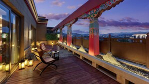 A rooftop terrace with a wooden deck, seating area, and decorative pillars. - Hilton Shigatse (Shigatse)