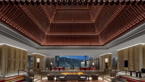A spacious lobby with a central seating area, a fire feature, and a view of mountains. - Hilton Shigatse (Shigatse)