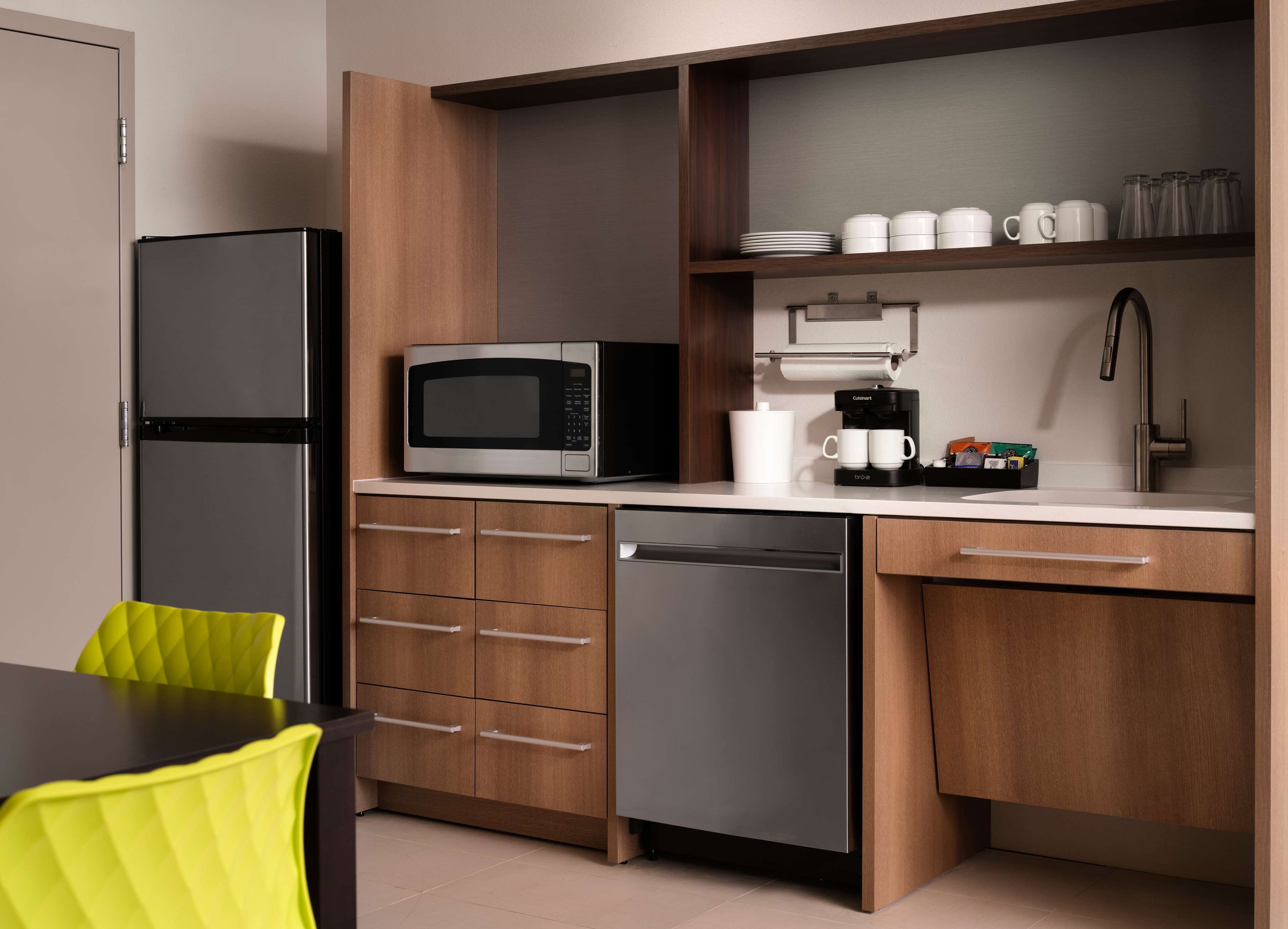 A modern kitchen with a refrigerator, microwave, coffee maker, and a sink.