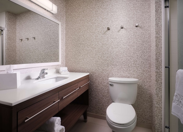 Un baño con lavamanos blanco, un espejo, inodoro y zona de ducha.