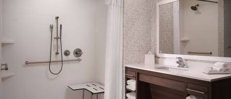 A modern bathroom with a walk-in shower, a vanity with a mirror, and a towel rack.