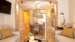 Uma sala de estar com sofá, mesa de centro com velas e área de jantar com lustre.