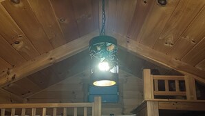 A wooden cabin interior with a bunk bed, a hanging light fixture, and a wooden ladder. - Log Cabin Sleeps four (Big Rapids)
