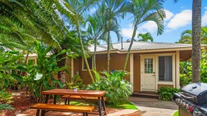 Una casa con patio, barbecue e tavolo con panche.