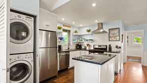Una cucina moderna con lavatrice e asciugatrice integrate, elettrodomestici in acciaio inossidabile e un'isola centrale.