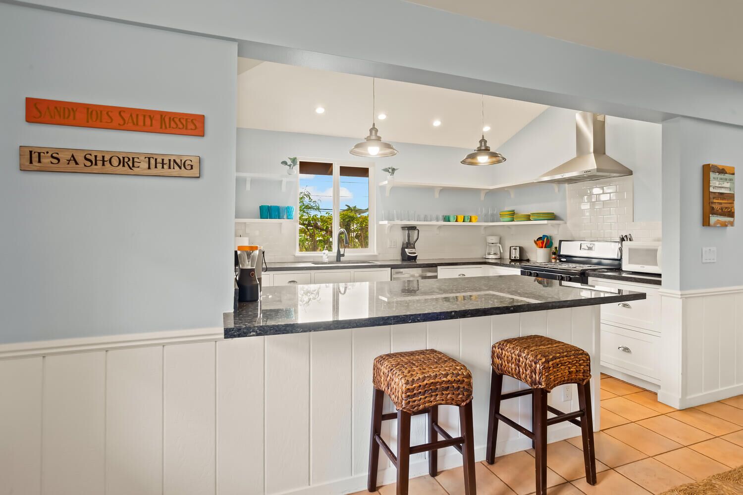 A kitchen with a large island, pendant lights, and a view of the outdoors.