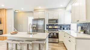 A modern kitchen with white cabinetry, stainless steel appliances, and a central island with bar stools.