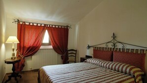 A bedroom with a bed, a nightstand, a lamp, and a window with curtains. - I Girasoli - Red apartment (San Marcello, Camerino)