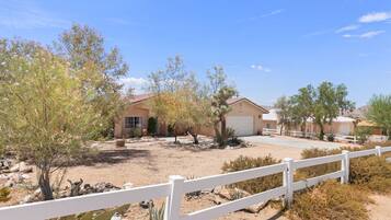 A residential area with houses, a white fence, and desert vegetation.