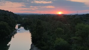 Un río que serpentea por una zona boscosa, con un atardecer en el horizonte.