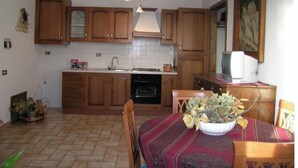 Een compacte keuken met houten kastjes, een spoelbak, een oven en een eethoek met een tafel gedekt voor twee personen.