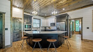 Una cocina moderna con una isla grande, taburetes de bar y techo de madera.