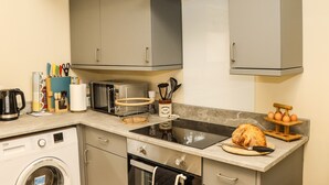 A compact kitchen with grey cabinets, a built-in oven, a microwave, and a sink. - The Old Mower Shed (Grantham)