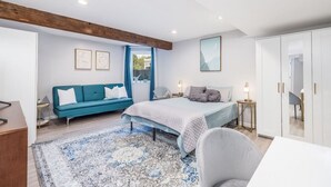 A modern bedroom with a bed, a blue sofa, a desk, and a wardrobe.