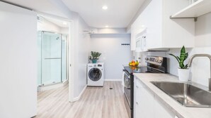 A compact kitchen with a washing machine, oven, and sink.