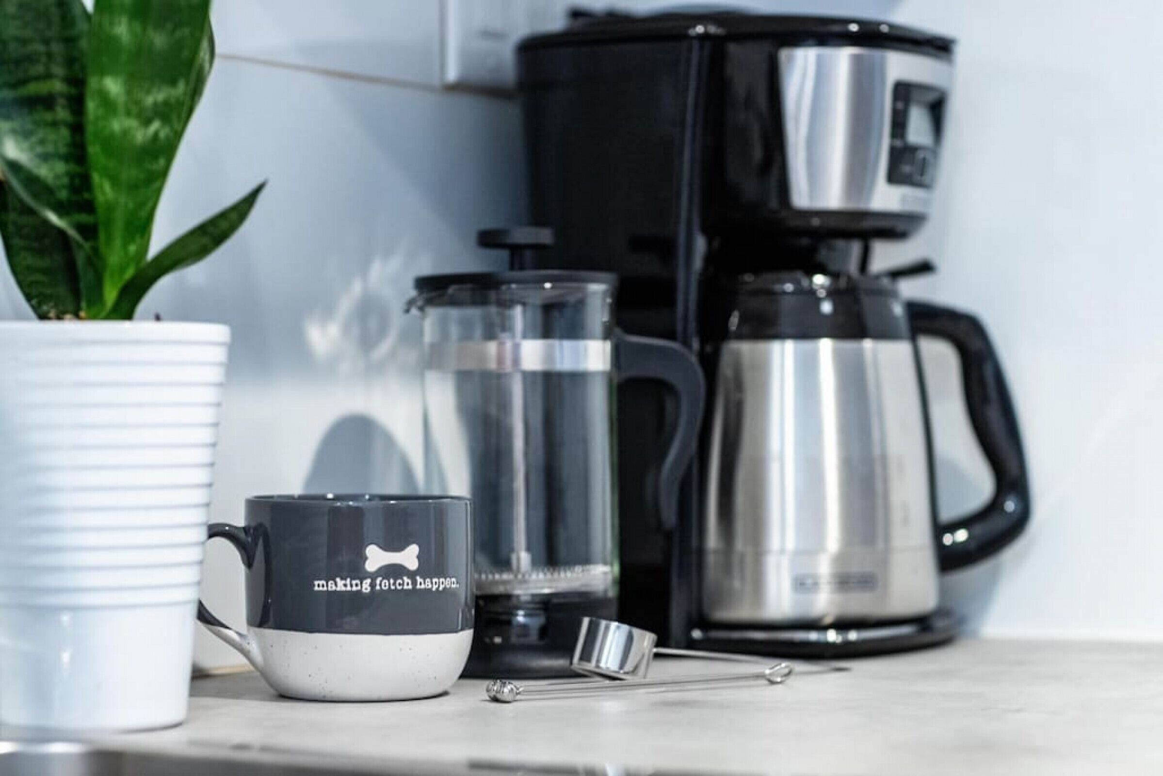 Eine Küchenarbeitsplatte mit einer Kaffeemaschine, einem Wasserkocher und einer Tasse.