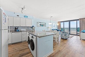 A modern kitchen with a central island, built-in appliances, and a dining area with a view.