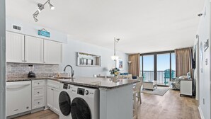 Eine moderne Küche mit Einbauwaschmaschine und -trockner, einem Essbereich mit Blick und einem Balkon mit Vorhängen.