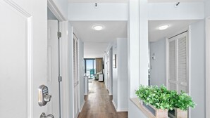 Ein Flur mit Holzboden, weißen Wänden und einer Pflanze auf einem Fensterbrett.
