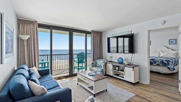 Ein modernes Hotelzimmer mit Balkon, einer Couch, einem Couchtisch, einem Fernseher und einem Bett.