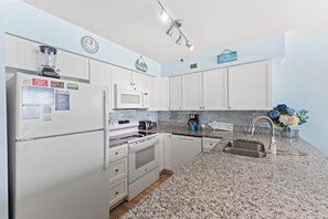 A modern kitchen with white cabinetry, a built-in microwave, a stove, and a sink.